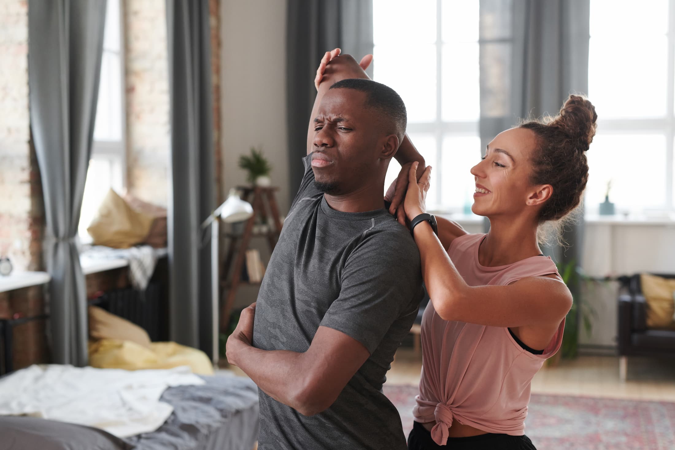 horizontal medium portrait of young caucasian woman helping her black boyfriend with stretching exercise 1